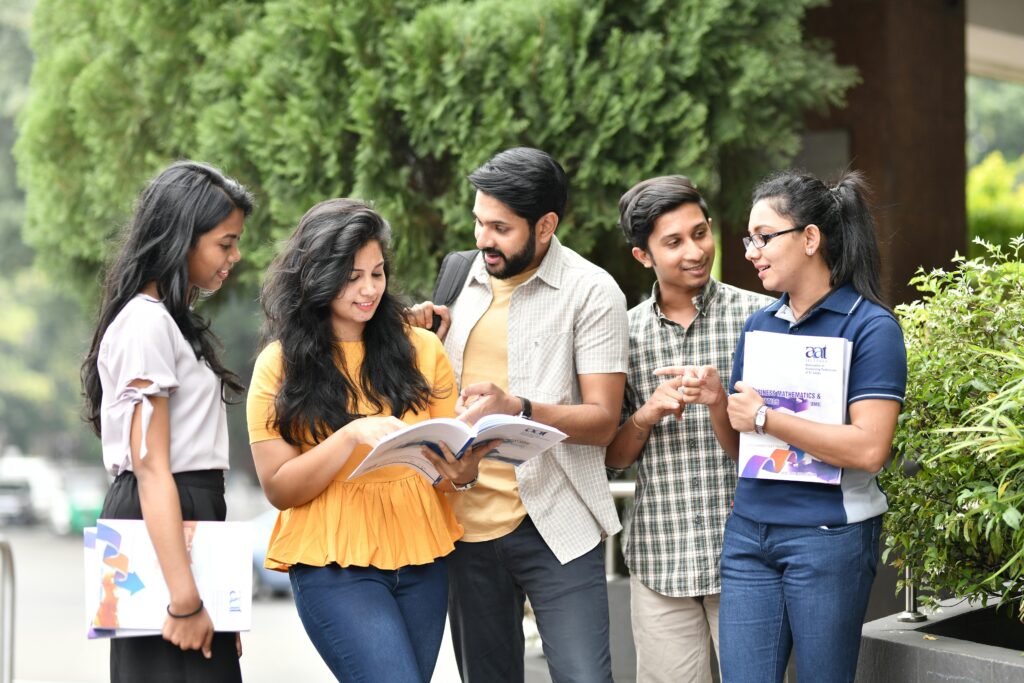 A group of diverse college students engaged in outdoor group study session, sharing books and ideas.
